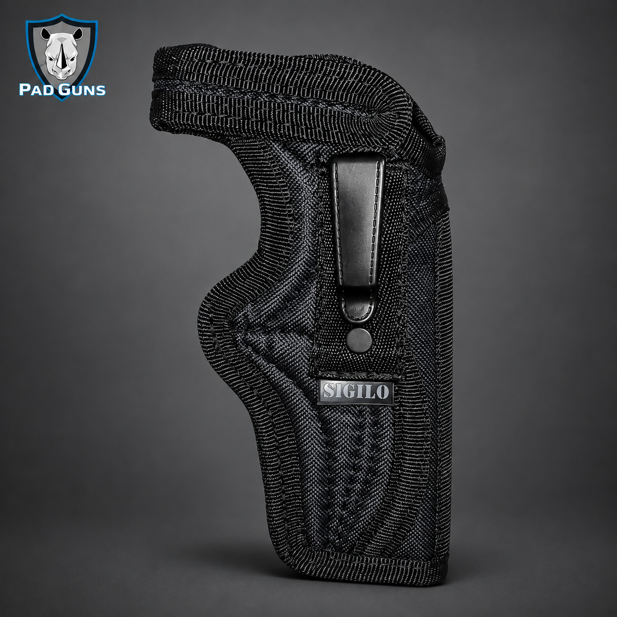 Funda interna táctica para revólver marca Sigilo en tejido sintético negro con costuras reforzadas, clip posterior rígido de cuero negro y etiqueta Sigilo lateral, vista de perfil sobre fondo gris, logo PaD Guns